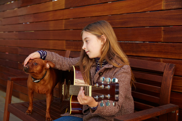 Os cães gostam de música? Veja como acalmar cachorro estressado! 1 kid girl playing guitar with dog winter beret 79295 6583