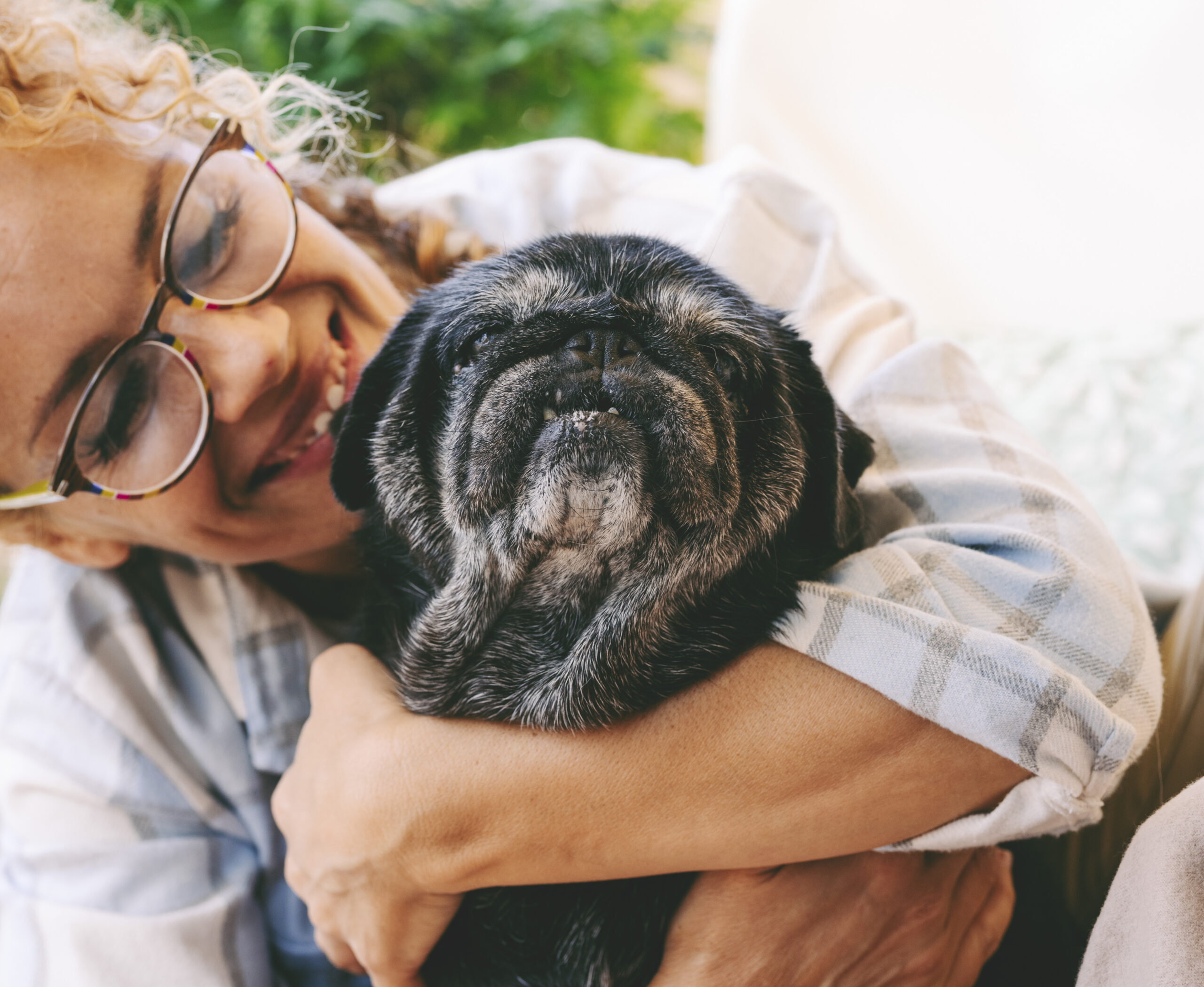 Cheerful woman hugging black old dog with love and freindship. A