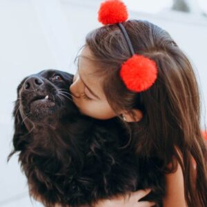 Menina abraçando e dando beijo no cachorro. Foto: Canva.
