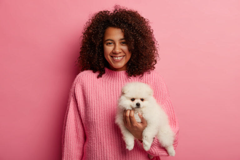 adoravel senhora de pele escura em um sueter de trico sendo amiga cachorro usa um sueter rosa